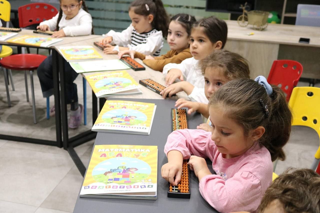 Children practicing mental arithmetic with abacuses and workbooks in an Abakus partner classroom